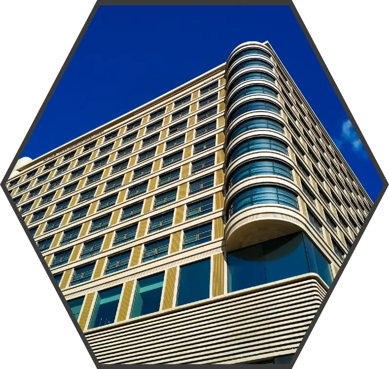 The exterior of a multi story building with yellow panelling on a bright sunny day. The angle is taken from a worms-eye view.