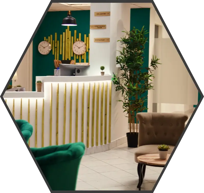 A brightly lit, vacant, hotel reception area. The front desk is white with a turqouise back wall