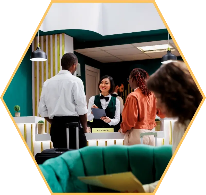 A couple are standing at a hotel reception desk. The receptionist is smiling at them.